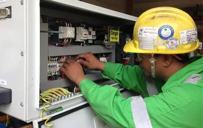 Jenmon Technician wearing hard hat inspecting crane panel