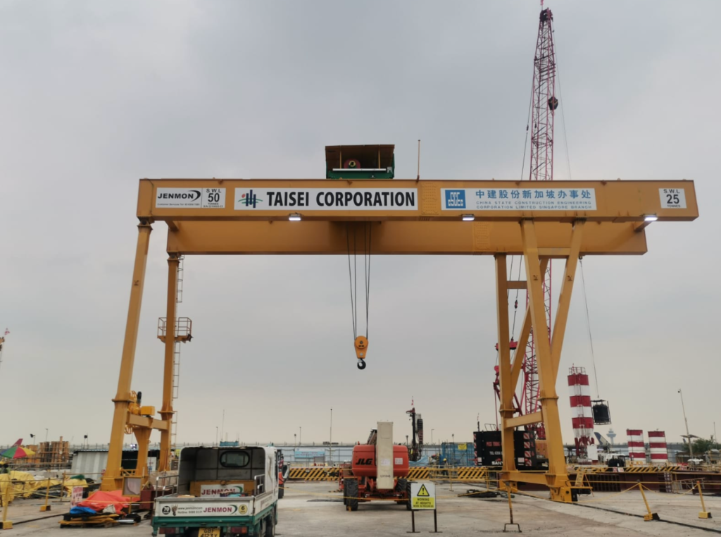 Large yellow gantry crane at a construction site with a hanging hook