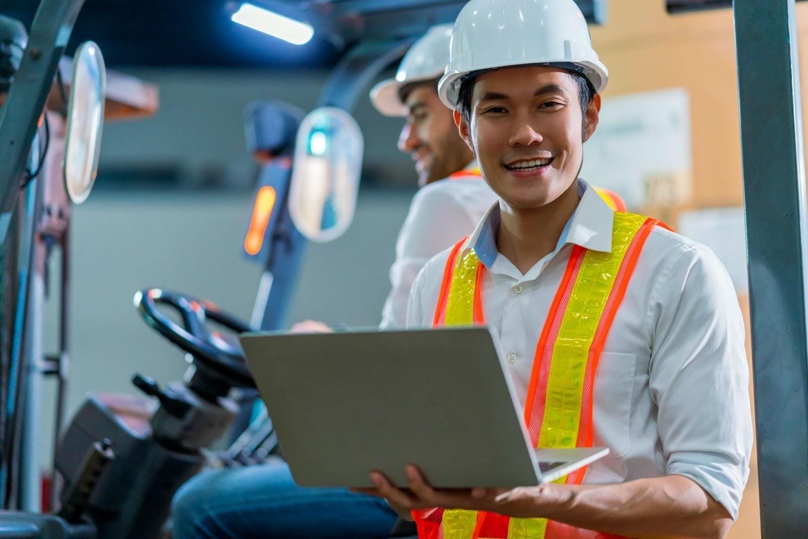 Asian technician in the warehouse facility using his laptop