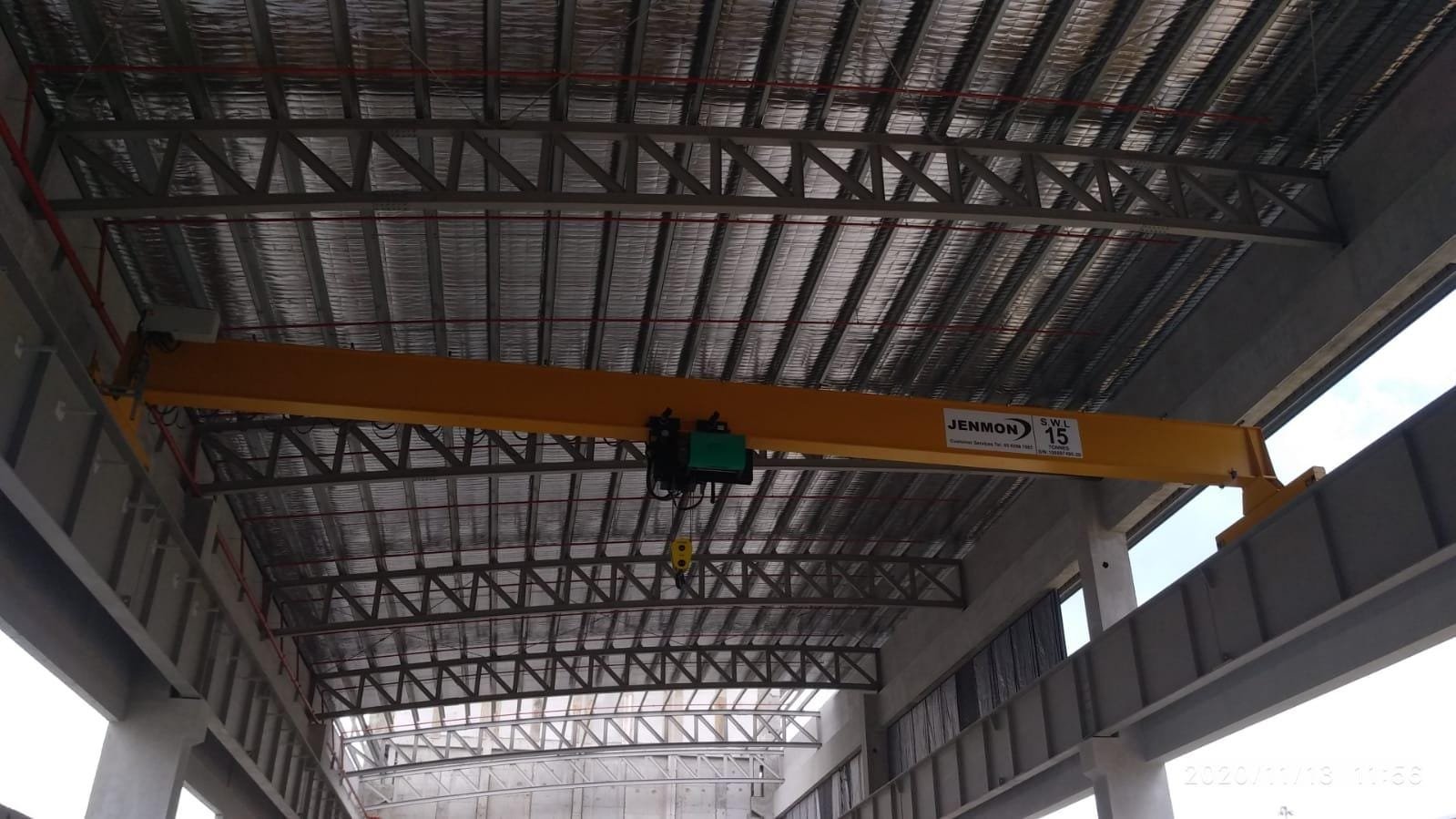 A green Jenmon hoist attached to a crane in a work site